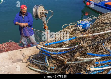 Un pêcheur répare et fixe ses filets après avoir pêché dans la mer Adriatique. Puglia, Italie, Europe Banque D'Images