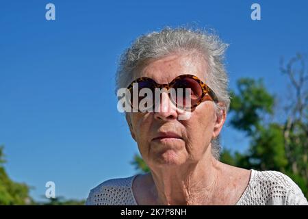 Une vieille femme de haut niveau se bronzer dans le parc public Banque D'Images