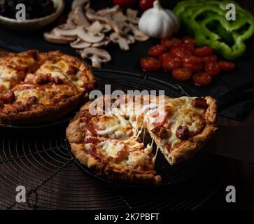 Vue rapprochée de deux pizzas à plat profond avec une tranche prise d'une. Banque D'Images