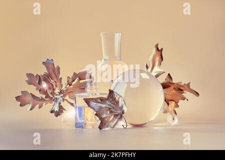 Fond d'automne Biophile. Feuilles d'érable doré déformées par des pots en verre transparent, de petites bouteilles. Éléments floraux beige orange monochrome Banque D'Images