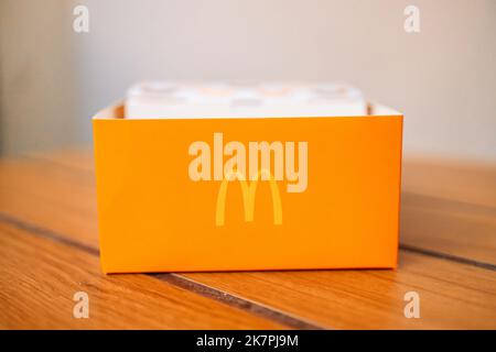 Cracovie, Pologne - 25 août 2022 : boîte en papier jaune avec logo McDonald's sur la table du restaurant McDonald's. Banque D'Images