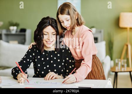 Portrait d'une mère heureuse et d'une fille qui dessinant des photos ensemble dans le cadre de la maison Banque D'Images