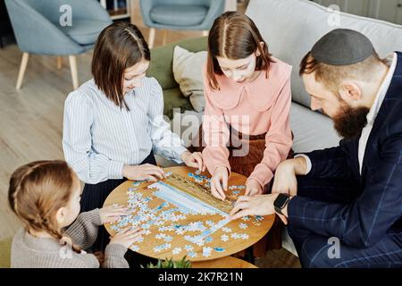 Vue en grand angle de la famille juive jouant ensemble au jeu de puzzle à la maison Banque D'Images