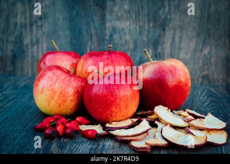 Les pommes, les pommes séchées et les hanches roses se trouvent sur une table en bois sombre automne Banque D'Images