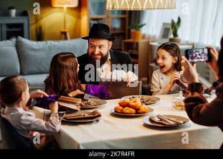 Portrait de famille juive moderne partageant des cadeaux à la table du dîner dans un cadre confortable Banque D'Images