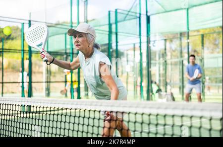 Femme âgée jouant au paddleball sur un terrain extérieur Banque D'Images