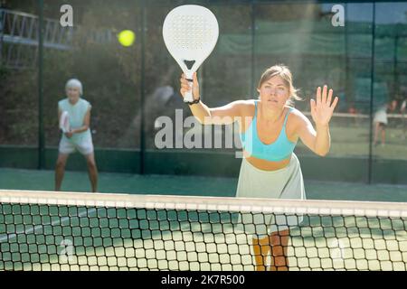 Jeune femme jouant au jeu de paddleball amical sur un terrain extérieur Banque D'Images