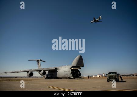 ÉTATS-UNIS Les aviateurs affectés à l'escadron d'intervention en cas d'urgence 921st effectuent un déchargement à partir d'un C-5M Super Galaxy alors que les moteurs fonctionnent tandis qu'un KC-10 Extender vole au-dessus pendant l'exercice Dragon Spark à la base aérienne de Travis, en Californie, le 14 octobre 2022. L'exercice Dragon Spark a offert aux unités de l'aile 60th de la mobilité aérienne et de l'aile 621st de l'intervention en cas d'urgence l'occasion de synchroniser les opérations en vue d'une catastrophe nationale. (É.-U. Photo de la Force aérienne par Nicholas Pilch) Banque D'Images