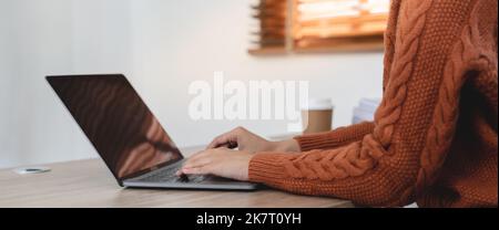 Gros plan sur les mains de femme tapant sur ordinateur portable clavier sur la table à la maison Banque D'Images