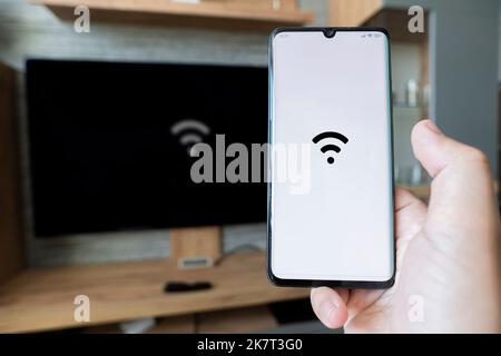 main mâle tenant un smartphone. Contrôlez la TV avec un smartphone. Connectivité entre Smart tv et un smartphone via une connexion wi-fi. Pour distribuer le i Banque D'Images