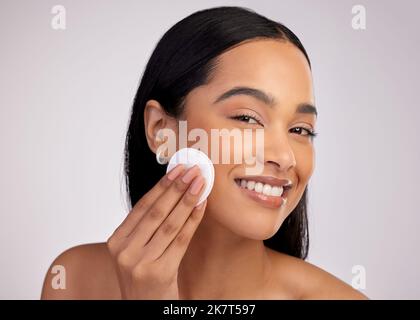 Prendre soin de ces pores. Portrait court d'une jeune femme attrayante exfoliant son visage sur fond rose. Banque D'Images