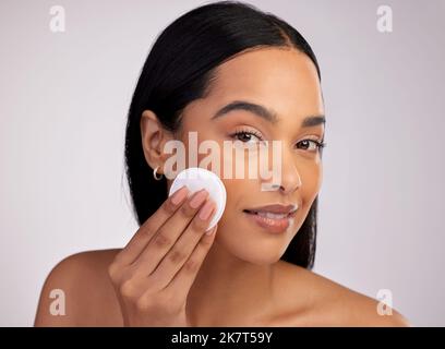 Exfoliation du visage. Portrait court d'une jeune femme attrayante exfoliant son visage sur fond rose. Banque D'Images