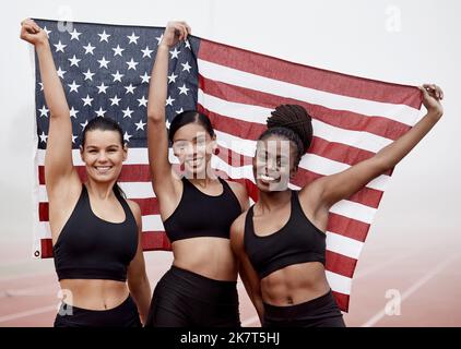 Plus fort sur la piste et en dehors. les athlètes féminins célèbrent leur victoire tout en tenant un drapeau. Banque D'Images