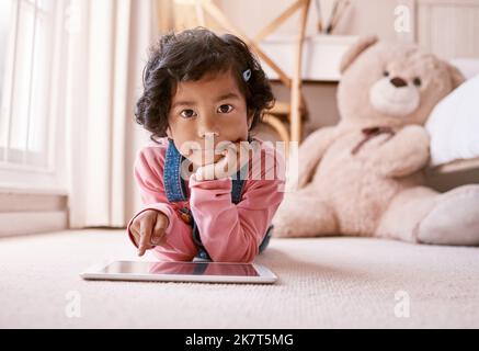 Je dispose d'un peu de temps pour la tablette. une petite fille utilisant une tablette numérique à la maison. Banque D'Images