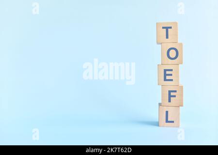 TOEFL ou test de l'anglais comme concept d'examen de système de test de langue étrangère. Blocs de bois typographie à plat sur fond bleu. Banque D'Images
