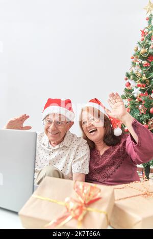 Un couple hispanique d'âge mûr accueille ses proches par appel vidéo pendant les fêtes à l'aide d'un ordinateur portable. Concepts: La joie de partager pendant les vacances, le Banque D'Images