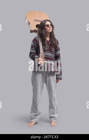 Jeune femme hippie debout et tenant sa guitare acoustique, portrait pleine longueur Banque D'Images