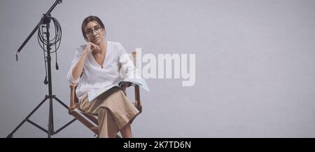 Cinéaste professionnel confiant assis sur la chaise du réalisateur et tenant un scénario de jeu: École de théâtre et le concept de l'industrie cinématographique, espace de copie Banque D'Images