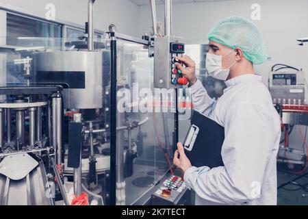 le personnel de l'ingénieur de l'usine agroalimentaire fait fonctionner la machine sur la chaîne de production. industrie des produits à boire. Banque D'Images