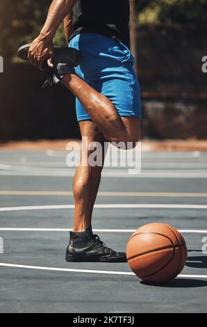 Fitness, basket-ball et homme qui étire les jambes sur le terrain extérieur pour la préparation musculaire avec l'entraînement. Musclé, fort et athlète masculin avec debout chaud Banque D'Images