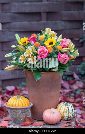 bouquet de roses roses, tournesols, fleurs de nénuphars et safflovers en terre cuite dans le jardin d'automne Banque D'Images