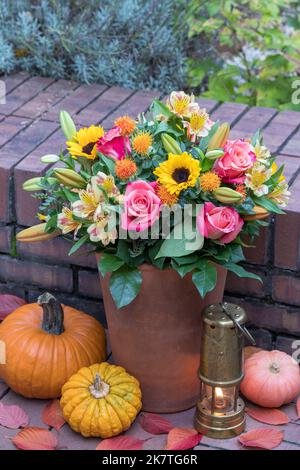 bouquet de roses roses, tournesols, fleurs de nénuphars et safflovers en terre cuite dans le jardin d'automne Banque D'Images