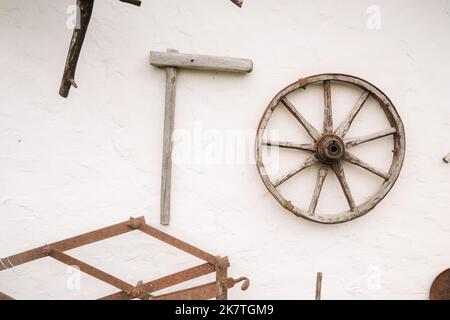 Un vieux mur en bois d'une maison dans le village et anciennes roues de charrette, outils, etc Banque D'Images