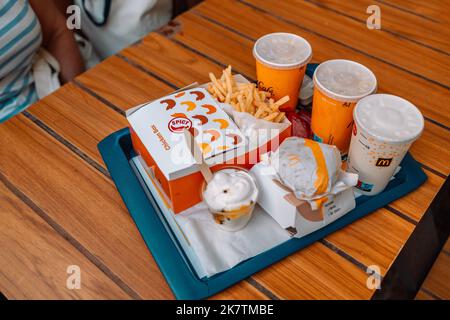 Cracovie, Pologne - 25 août 2022 : la nourriture McDonald's sur la table sur fond de buisson vert. Menu Big Mac. Sac McDonald's à côté d'un verre de cola, frit Banque D'Images