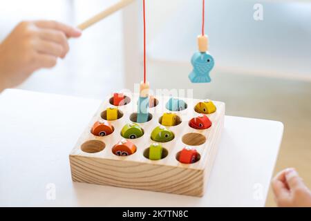 Les enfants jouent et trouvent le nombre correspondant dans le jeu de pêche magnétique en bois, en utilisant le poteau de pêche en bois fourni avec des aimants pour fixer le protocole d'entente Banque D'Images