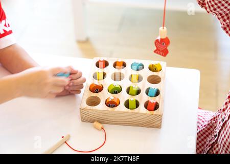 Les enfants jouent et trouvent le nombre correspondant dans le jeu de pêche magnétique en bois, en utilisant le poteau de pêche en bois fourni avec des aimants pour fixer le protocole d'entente Banque D'Images