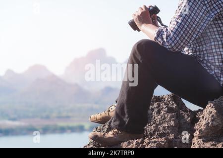 Le randonneur est assis en haut de la montagne avec les jumelles Banque D'Images