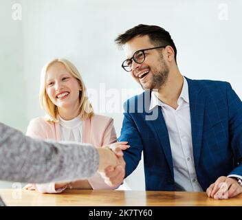 un jeune couple qui tremble les mains traite contrat d'investissement immobilier agent d'accord d'affaires poignée de main signature Banque D'Images