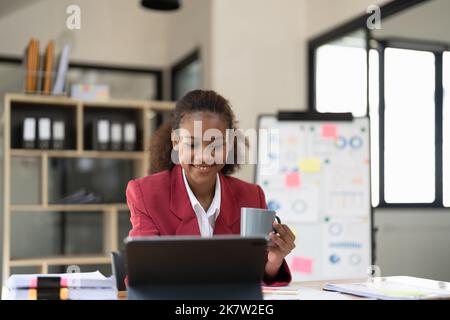 Smiling afro businesswoman working on laptop in modern office Banque D'Images