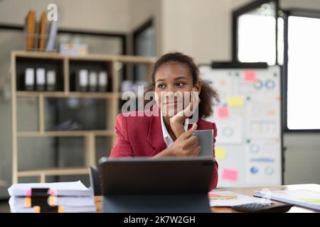 Smiling afro businesswoman working on laptop in modern office Banque D'Images