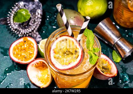 Doux cocktail tropical coloré avec fruits de la passion, citron vert et menthe. Long buveur alcool passion fruit boire sur fond sombre espace de copie Banque D'Images