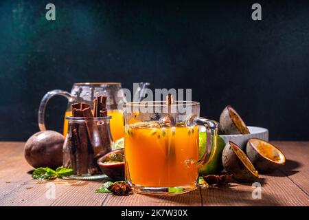 Thé chaud aux fruits de la passion avec jus fruité, cannelle, citron vert, sur fond de bois avec fruits de la passion frais et épices Banque D'Images