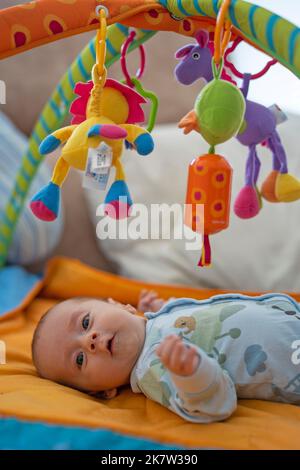 Bébé jouant sur la salle de sport colorée Banque D'Images