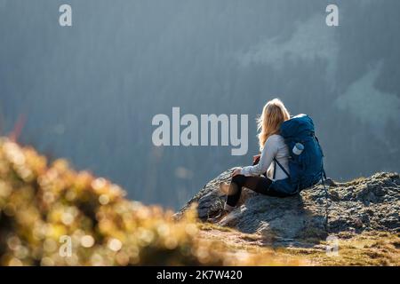 Femme avec sac à dos assis sur le sommet de la montagne. Repos pendant la randonnée. Femme randonneur jouissant d'une vue sur la nature Banque D'Images