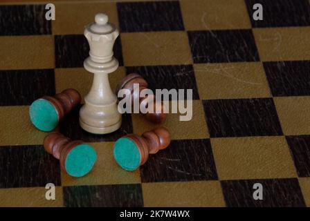 Échecs - un roi blanc se tient sur le plateau d'échecs entouré de pions bruns tombés - il n'y a pas d'autres pièces sur le plateau. Le contraste est frappant. Banque D'Images