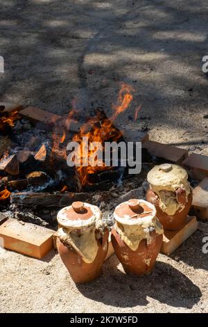 Pots d'argile avec la nourriture à l'intérieur étant cuits sur un feu lent dans un foyer, à un festival de la nourriture à Estoril, Lisbonne, Portugal. Banque D'Images