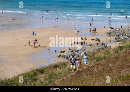 Une jeune famille marchant sur le sentier de la côte surplombant les vacanciers se détendant sur la plage à Polly Porth Joke sur la côte à Newquay dans Cornwall dans le TH Banque D'Images