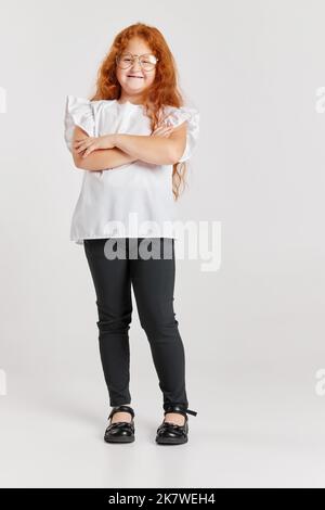 Petit fashionista. Portrait d'une petite fille à tête rouge portant des talons de mère isolée sur fond blanc. Émotions des enfants, expressions du visage Banque D'Images