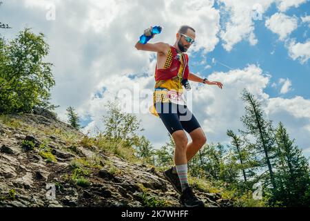 Bannoe, Russie - 31 juillet 2022 : un coureur de sexe masculin part en descente de montagne abrupte sur le sentier sauvage de MMK Banque D'Images