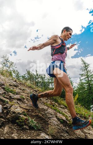 Bannoe, Russie - 31 juillet 2022: Athlète coureur courir la descente de montagne abrupte dans le sentier sauvage de MMK Banque D'Images