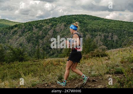 Bannoe, Russie - 31 juillet 2022: Athlète féminine coureur course descente de montagne dans le sentier sauvage de MMK Banque D'Images