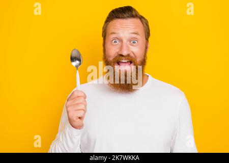 Photo portrait de jeune gars beau tenir cuillère prêt manger des aliments sains vêtu pull blanc tendance isolé sur fond jaune Banque D'Images