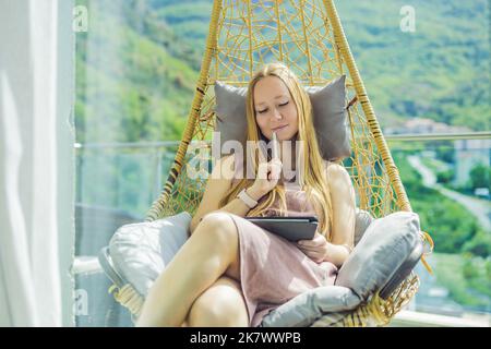 Femme caucasienne assise sur la terrasse travaillant de la maison à l'aide d'un ordinateur portable. La jeune femme enseigne une langue étrangère ou apprend une langue étrangère sur Banque D'Images