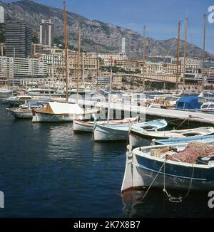 1960s, de petits voiliers historiques amarrés à Port Hercules, Monaco, avec les immeubles de luxe au loin. Utilisé depuis les temps anciens, le port moderne a été achevé en 1926 et est le seul port en eau profonde de la principauté. Banque D'Images