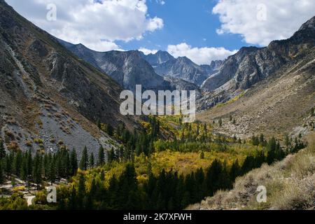 Vue panoramique sur les sommets de montagne sous un ciel bleu nuageux avec un pré en dessous dans les couleurs de l'automne. Banque D'Images