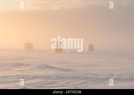 Pêche sur glace dans un port gelé dans la région rurale de l'Île-du-Prince-Édouard, Canada. Banque D'Images